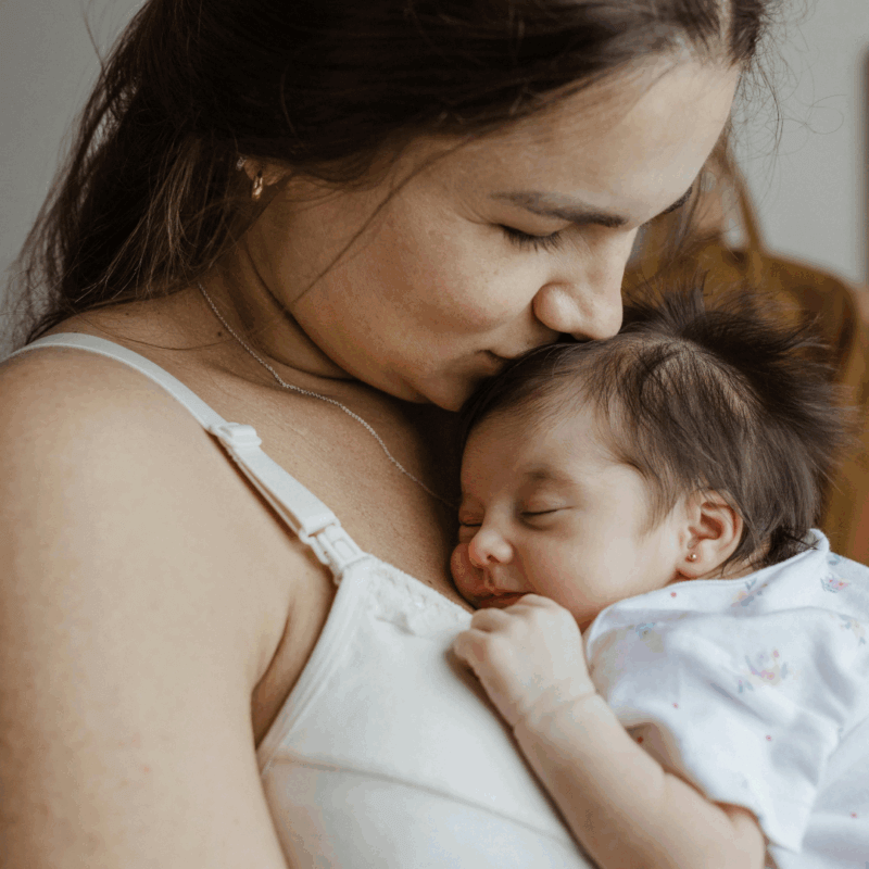 mum carrying and kissing a newborn